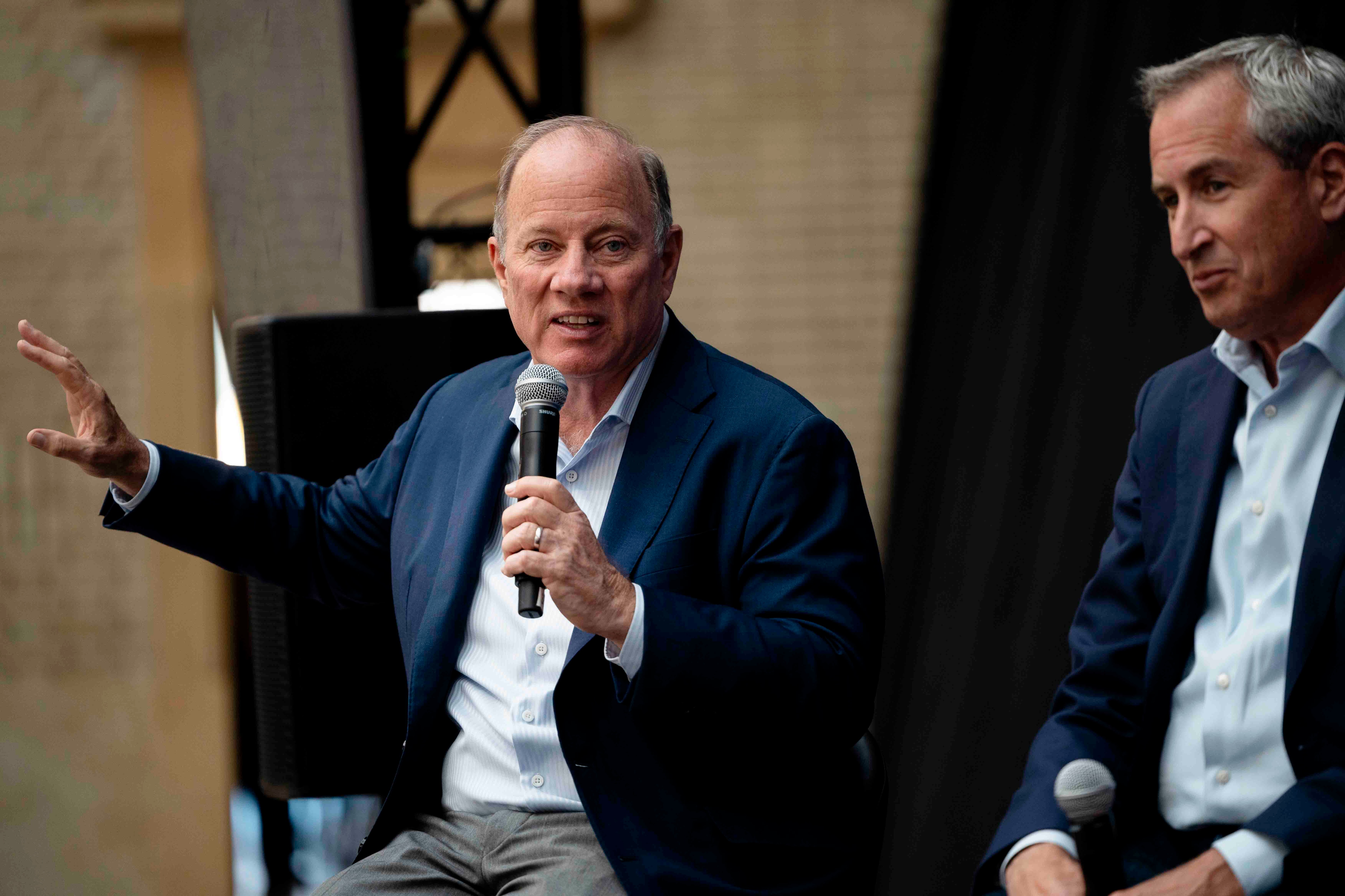 A man in business attire holds a microphone